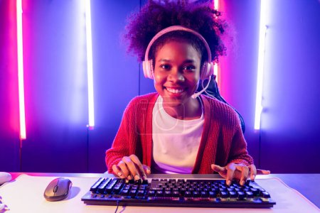 Photo for Gaming streamer, African girl playing online fighting with Esport skilled team wearing headphones in neon color lighting room. Talking other players planing strategies to win competitors. Tastemaker. - Royalty Free Image