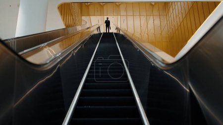 Photo for Professional business man using phone calling while using escalator. Skilled caucasian executive manager talking to business team to report and discuss marketing idea or plan. Front view. Exultant. - Royalty Free Image