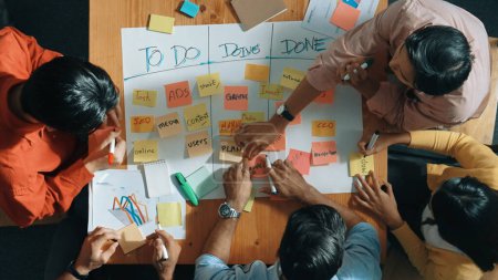 Photo for Top view of people writing and making scrum task board while writing marketing and planning strategy at colorful sticky notes. Smart team manage work performance by using kanaban board. Convocation. - Royalty Free Image