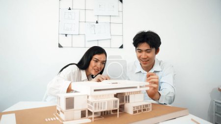Photo for Closeup image of cooperate professional architect team working together by measuring house model on meeting table with architectural document and house model. Creative design concept. Immaculate. - Royalty Free Image