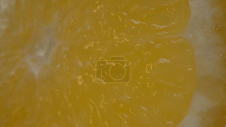 Téléchargez les photos : La macro photographie d'une orange tranchée de couleur orange vif et visible dans la chair juteuse des agrumes. La chair de l'orange apparaît charnue, laissant entendre qu'elle est juteuse. Comestible. - en image libre de droit