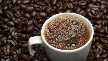 Primer plano de la burbuja aromática de café caliente en la taza con fondo negro. Café caliente o espresso se vierte en taza de café blanco cayendo en agua hervida con fondo negro separado. Comestible.