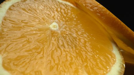 Téléchargez les photos : Une capture macrographique d'une tranche d'orange, placée sur une toile de fond noire élégante et isolée, se déploie comme un chef-d'œuvre visuel d'allure d'agrumes. Une tranche d'orange avec un fond noir. Comestible. - en image libre de droit