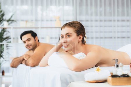 Photo for Blissful couple customer having exfoliation treatment in luxury spa salon with warmth candle light ambient. Salt scrub beauty treatment in health spa body scrub. Quiescent - Royalty Free Image