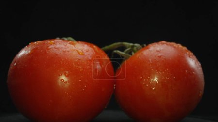 Macrography, tomatoes nestled within a rustic wooden basket are showcased against a dramatic black background. Each close-up shot captures the rich colors and textures of the tomatoes. Comestible.