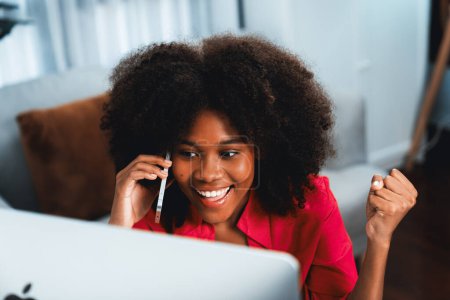 African woman talking with coworker or friend on the phone and looking at the screen with happy face. Achievement for promoting job position in the company with the good news life. Tastemaker.