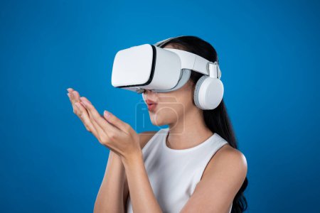 Photo for Smart female standing with blue background wearing VR headset connecting metaverse, futuristic cyberspace community technology. Elegant woman excited seeing generated virtual scenery. Hallucination. - Royalty Free Image