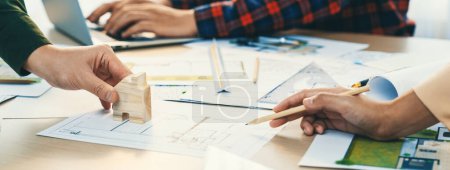 Photo for Skilled architect team using architectural equipment during colleague discussion about building design at meeting table with blueprint scatter around. Closeup. Focus on hand. Delineation. - Royalty Free Image