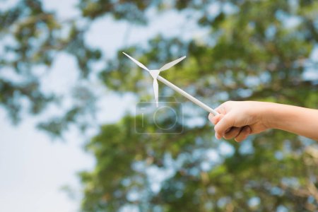 Téléchargez les photos : Petit garçon tenant un moulin à vent ou un modèle de maquette d'éolienne pour promouvoir l'utilisation de technologies d'énergie propre et renouvelable pour la génération future et la Terre durable. Pneumatique - en image libre de droit