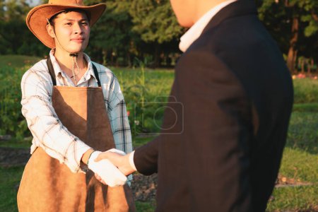 Eco-businessman handshake with farmer, eco-friendly farming practice and clean agricultural technology. Cooperation between farmer and CSR company for farm subsidize with environment protection. Gyre