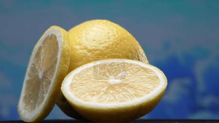 Eine Scheibe frischer Zitrone, leuchtend gelb und lebhaft zitronig, liegt offen. Das Fruchtfleisch, das vor erfrischendem Saft glitzert, enthüllt sein segmentiertes Inneres. Die Essenz der Lebendigkeit der Zitrusfrüchte. Komestibel.