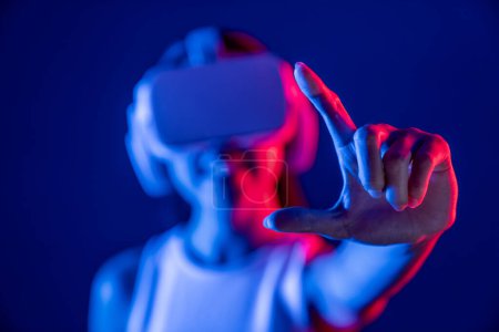 Foto de Mujer de pie rodeada de neón luz desgaste VR auriculares que conectan metaverso, futurista tecnología de la comunidad del ciberespacio, extendiendo índice y dedo pulgar interactuando objeto virtual. Alucinaciones. - Imagen libre de derechos