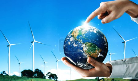 Concept of sustainability development by alternative energy. Man hand take care of planet earth with environmentally friendly wind turbine farm and green renewable energy in background. uds