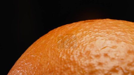 Makrografie, die komplizierte Struktur einer Orange vor einem auffallend schwarzen Hintergrund, stiehlt das Rampenlicht. Nahaufnahme fängt die einzigartigen Muster und Details der Orangenoberfläche ein. Komestibel.