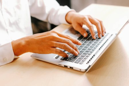 Téléchargez les photos : Homme d'affaires tapant à la main sur le clavier de l'ordinateur d'un ordinateur portable au bureau. Concept d'entreprise et de finance. uds - en image libre de droit