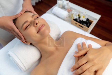 Photo for Caucasian woman enjoying relaxing anti-stress head massage and pampering facial beauty skin recreation leisure in dayspa modern light ambient at luxury resort or hotel spa salon. Quiescent - Royalty Free Image