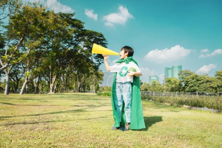 Foto de El joven superhéroe con símbolo de reciclaje y capa hace un anuncio con el orador sobre la conciencia ambiental para la gestión del reciclaje de residuos ecológicos como su misión de salvar la Tierra. Gyre. - Imagen libre de derechos