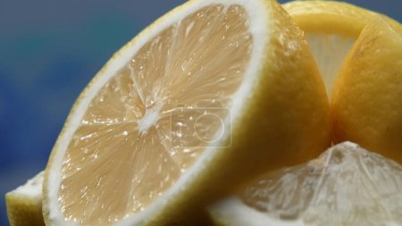 Eine Zitronenscheibe, leuchtend gelb und lebhaft zitronig, liegt offen. Das gelbe Fruchtfleisch mit erfrischendem Saft offenbart sein segmentiertes Inneres. Die Essenz der Lebendigkeit der Zitrusfrüchte. Zeitlupe. Komestibel.