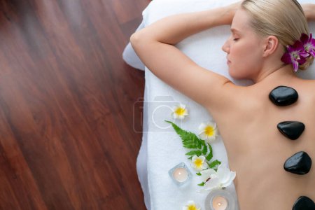 Photo for Panorama top view hot stone massage at spa salon in luxury resort with day light serenity ambient, blissful woman customer enjoying spa basalt stone massage glide over body. Quiescent - Royalty Free Image