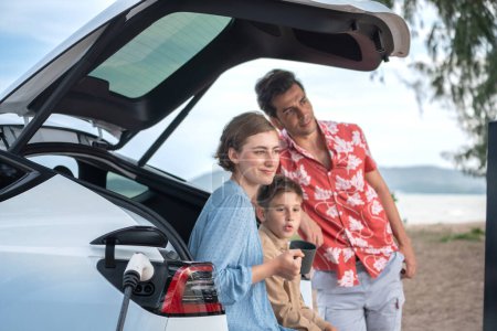 Photo for Family vacation trip traveling by the beach with electric car, happy family recharge EV car, enjoying outdoor camping coffee. Seascape travel and eco-friendly car for clean environment. Perpetual - Royalty Free Image