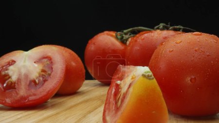 Photo for Macrography, slices of tomato rest elegantly on a rustic cutting board against a dramatic black background. Each close-up shot captures the juicy texture and rich colors of the tomatoes. Comestible. - Royalty Free Image