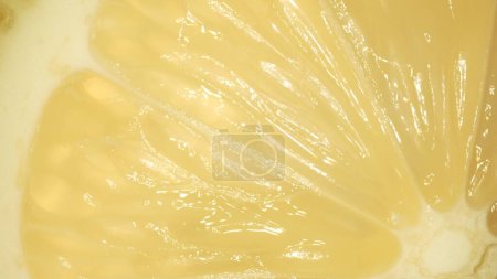 The macro photography of a sliced fresh lemon with vibrant yellow color and visible in the juicy flesh of the citrus fruit. The flesh of the lemon appears plump, hinting at its juiciness. Comestible.