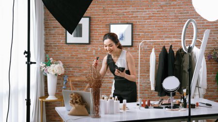 Photo for Woman influencer shoot live streaming vlog video review vivancy makeup social media or blog. Happy young girl with cosmetics studio lighting for marketing recording session broadcasting online. - Royalty Free Image
