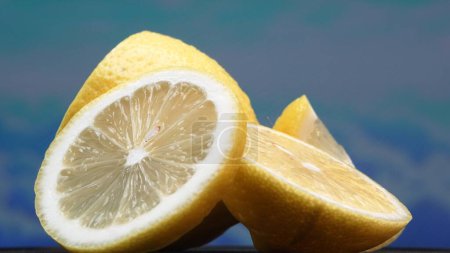 Eine Zitronenscheibe, leuchtend gelb und lebhaft zitronig, liegt offen. Das gelbe Fruchtfleisch mit erfrischendem Saft offenbart sein segmentiertes Inneres. Die Essenz der Lebendigkeit der Zitrusfrüchte. Zeitlupe. Komestibel.