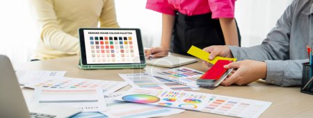 Ein Porträt der Kreativität Grafik-Designer-Team wählen Sie die passende Farbe für das Projekt, indem Sie Laptop auf dem Tisch mit Geräten und Design-Werkzeug herumstreuen in modernen Büros. Nahaufnahme. Bunt gemischt.