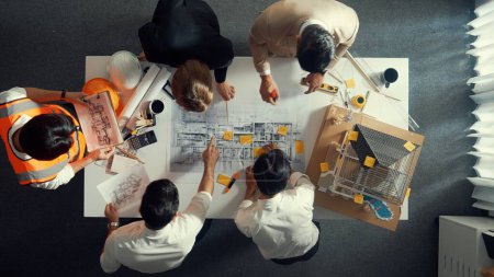 Photo for Top down view of skilled engineer team compare between blueprint and house plan. Aerial view of group of architect or designer discussing and point note to brainstorm about blueprint. Alimentation. - Royalty Free Image