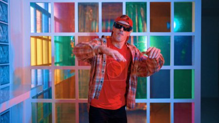 Photo for Funny break dancer moving freestyle step to hiphop while looking at camera. Crazy happy hipster dancing and performing street dancing while wear casual outfit and sunglasses in Led light. Regalement. - Royalty Free Image