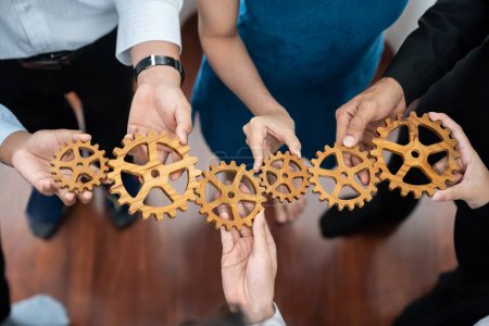 Photo for Office worker holding cog wheel as unity and teamwork in corporate workplace concept. Diverse colleague business people showing symbol of visionary system and mechanism for business success. Concord - Royalty Free Image