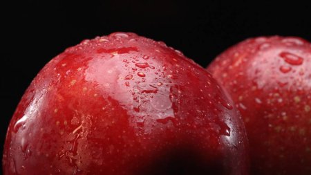 Una manzana roja fresca, con su pulpa blanca y crujiente, descansa dramáticamente sobre un fondo negro. La superficie lisa y crujiente de manzana, rodaja de manzana con fondo negro separado. Comestible.