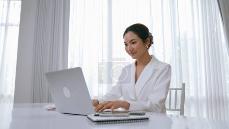 Foto de Joven empresaria sentada en el escritorio del espacio de trabajo usando un ordenador portátil para escribir contenido en línea en Internet o un secretario a distancia que trabaja desde casa. Vivancia - Imagen libre de derechos
