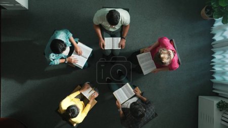 Photo for Top down view of prayer reading at bible book and sitting in circle with bible book on laps. Aerial view of diverse people looking at book while studying with faith, trust and hope, calm. Symposium. - Royalty Free Image