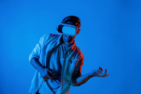 Photo for Caucasian man moving playing guitar gesture while wearing VR glass with neon light background. Gamer enter in metaverse or virtual reality simulated program by using technology innovation. Deviation. - Royalty Free Image