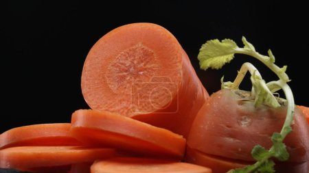 Téléchargez les photos : La macrographie, les carottes tranchées prennent le devant de la scène avec un fond noir, créant un contraste visuel saisissant. Chaque gros plan capture les détails complexes et les couleurs vibrantes de la carotte. Comestible. - en image libre de droit