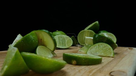 Close-up, a vibrant slice of fresh lime rests upon a rustic wooden cutting board, exuding freshness and vitality. The translucent membranes of the green lime slice placed on cutting board. Comestible.