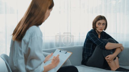 Photo for Sad PTSD woman patient in therapy for mental health with psychologist, depression or grief after life failure. Frustrated trauma young woman talking to prim psychologist about emotion in clinic - Royalty Free Image