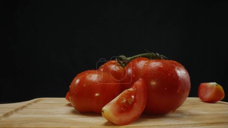 Photo for Macrography, slices of tomato rest elegantly on a rustic cutting board against a dramatic black background. Each close-up shot captures the juicy texture and rich colors of the tomatoes. Comestible. - Royalty Free Image