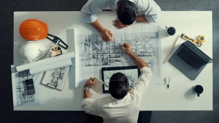 Photo for Top view of civil engineer working together to plan building design. Top down aerial view of skilled architect team sitting at table while manager talking and discussing about blueprint. Alimentation. - Royalty Free Image