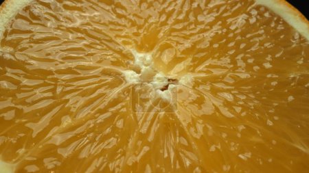Téléchargez les photos : Une capture macrographique d'une tranche d'orange, placée sur une toile de fond noire élégante et isolée, se déploie comme un chef-d'œuvre visuel d'allure d'agrumes. Une tranche d'orange avec un fond noir. Comestible. - en image libre de droit