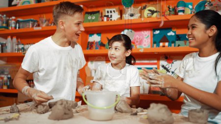 Photo for Happy diverse student laughing while caucasian girl modeling cup in pottery class or workshop. Caucasian highschool girl looking at boy while smiling boy attend in art lesson. Education. Edification. - Royalty Free Image