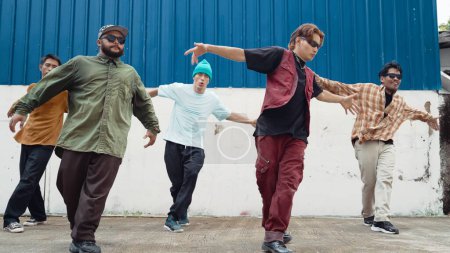 Foto de Grupo de coreógrafos de hip hop bailando danza callejera juntos en la pared. Jóvenes bailarines de break practicando break dance, moviéndose a ritmo moderno, expresan sensación de vivacidad. Exterior 2024. Endeavor. - Imagen libre de derechos