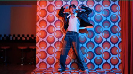 Photo for Asian break dancer moving to freestyle music and looking at camera at stage with balloon background. Professional hipster wearing casual outfit and fancy glasses while perform footstep. Regalement. - Royalty Free Image
