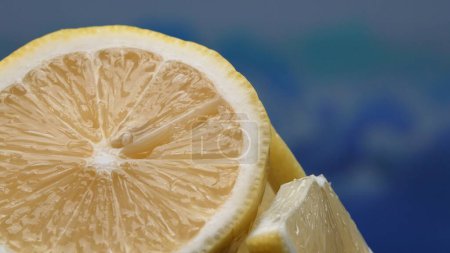 Eine Scheibe frischer Zitrone, leuchtend gelb und lebhaft zitronig, liegt offen. Das Fruchtfleisch, das vor erfrischendem Saft glitzert, enthüllt sein segmentiertes Inneres. Die Essenz der Lebendigkeit der Zitrusfrüchte. Komestibel.