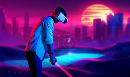 Téléchargez les photos : Homme caucasien jouant au golf en métaverse tout en portant des lunettes VR pour entrer dans le monde virtuel simulé. Beau joueur utilisant des lunettes de réalité virtuelle entrer dans le terrain de golf néon. L'innovation. Du sport. Déviation. - en image libre de droit