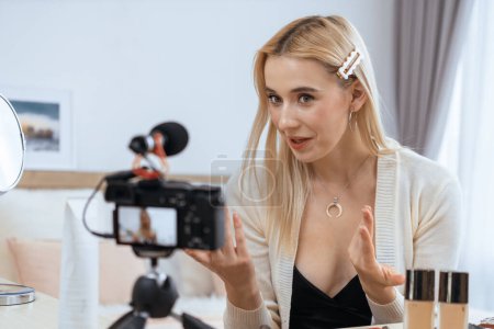 Mujer joven haciendo belleza y contenido de vídeo tutorial cosmético para las redes sociales. El blogger de belleza sonríe a la cámara mientras muestra cómo cuidar la belleza a la audiencia o seguidores. Blithe.