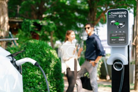 Photo for Young couple recharge electric cars battery from charging station in outdoor green city park in springtime. Rechargeable EV car for sustainable environmental friendly urban travel lifestyle.Expedient - Royalty Free Image