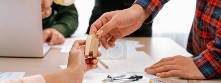 Téléchargez les photos : Une équipe d'architectes professionnels discute d'un projet architectural sur une table de réunion avec un plan directeur et des blocs de bois éparpillés dans un bureau moderne. Gros plan. Concentrez-vous. Délimitation. - en image libre de droit
